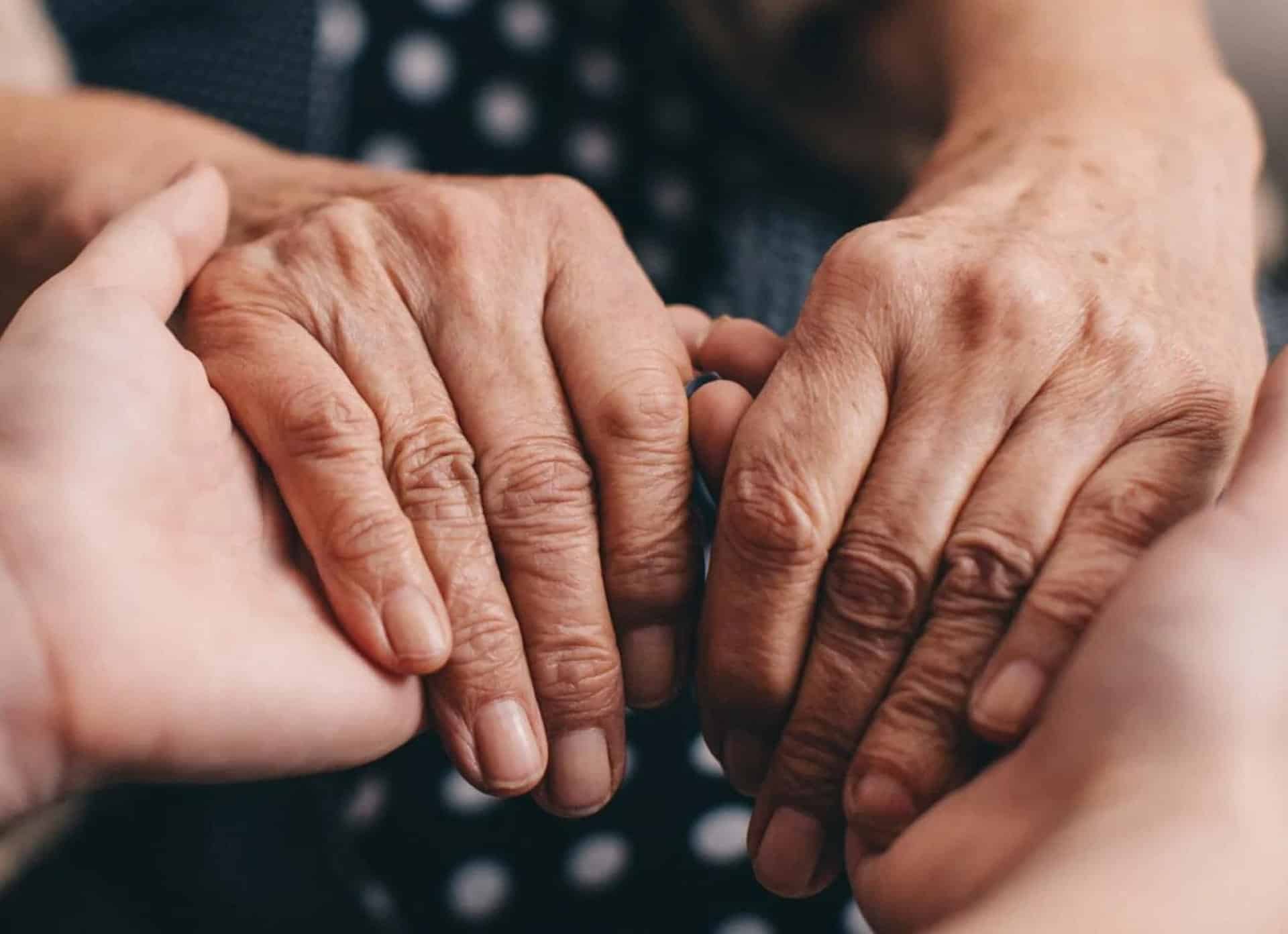 Close-up of elderly and young hands gently holding each other.