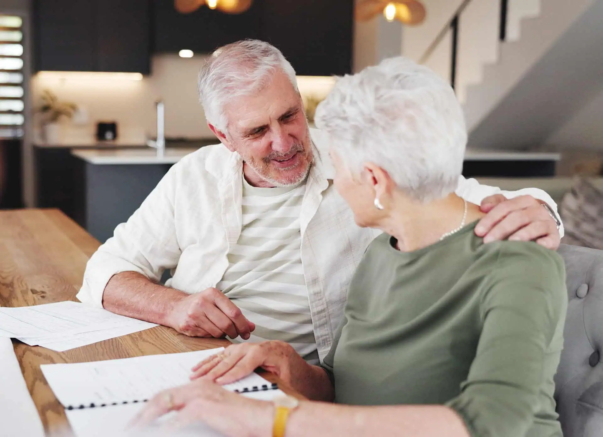 Elderly man and woman sharing a warm moment at a table.