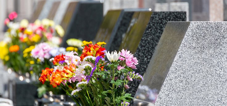 Vivid flowers and granite headstones at a cemetery memorial site.