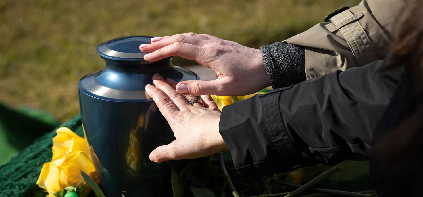 Person placing a vase on a memorial site outdoors.