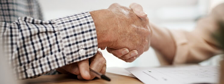 Close-up of two hands shaking, one older and one younger, in a comforting gesture.
