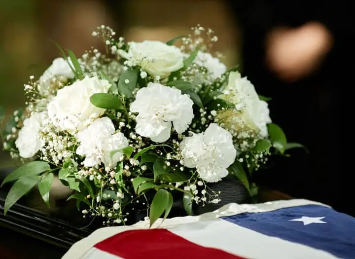 White floral arrangement with roses and baby's breath on a casket.