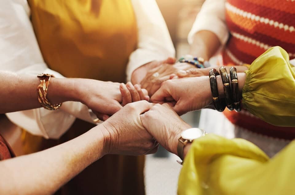 Group of diverse hands joined together in a circle, symbolizing unity and support.