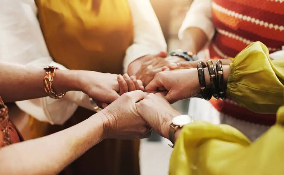 Group of diverse people holding hands together in a circle.