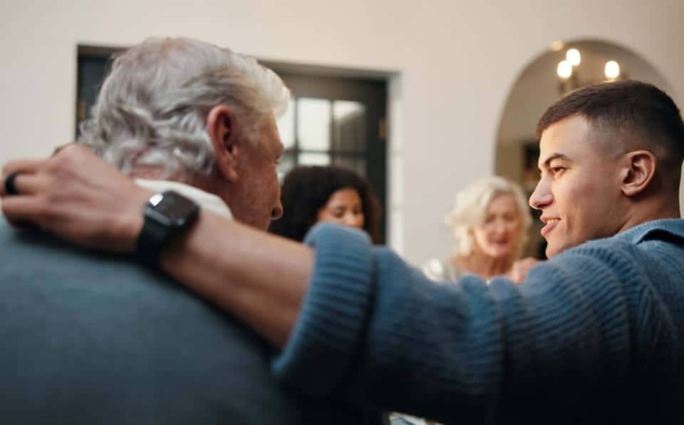 Two men sharing a warm moment at a memorial service in a chapel.