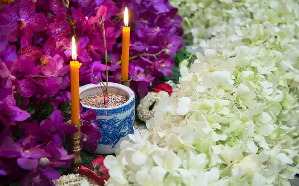 Colorful floral arrangement with candles at a memorial site.