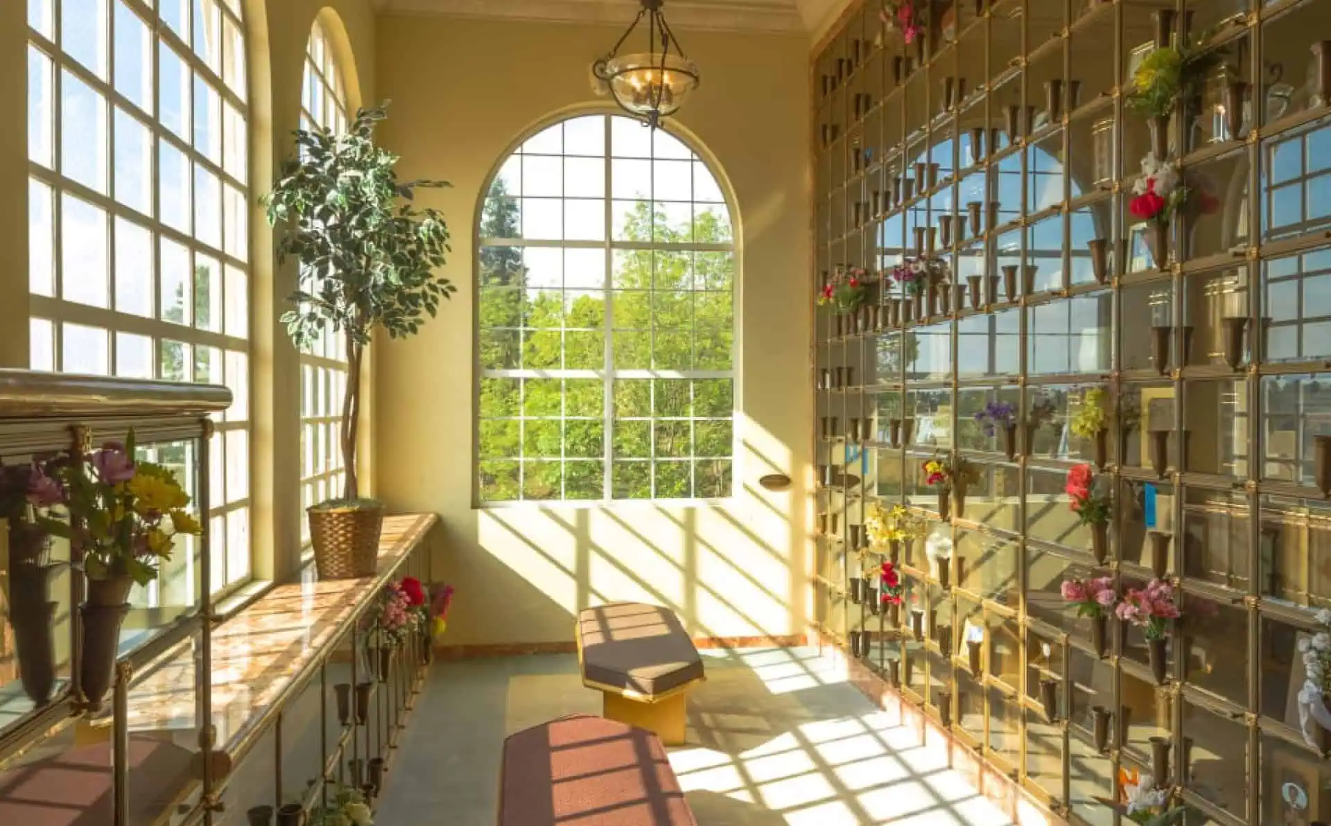 Bright columbarium with glass-front niches and sunlight streaming in.
