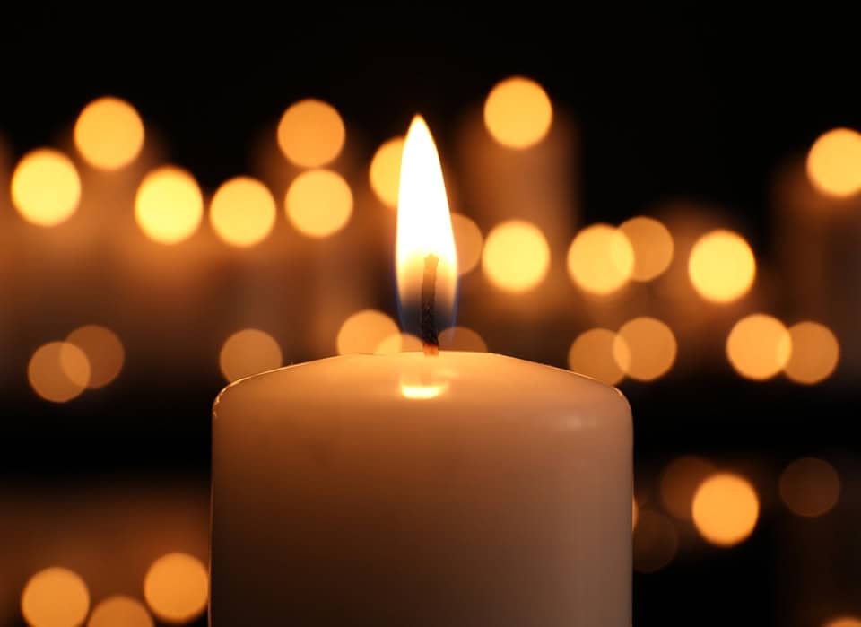 Close-up of a lit candle with blurred candle lights in the background.