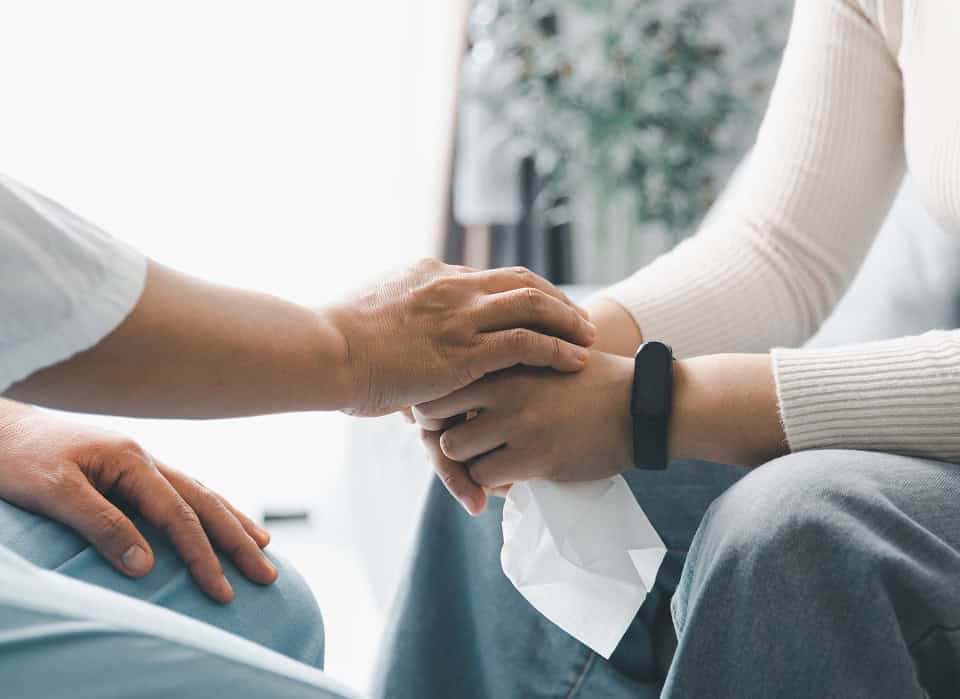 Person offering comforting hand to another person in a supportive gesture.