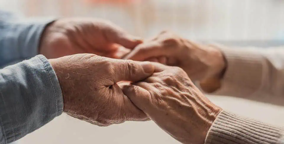 Close-up of two elderly hands gently holding each other.