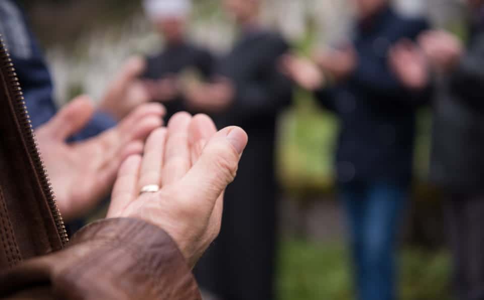 Close-up of hands in prayer during a memorial gathering.