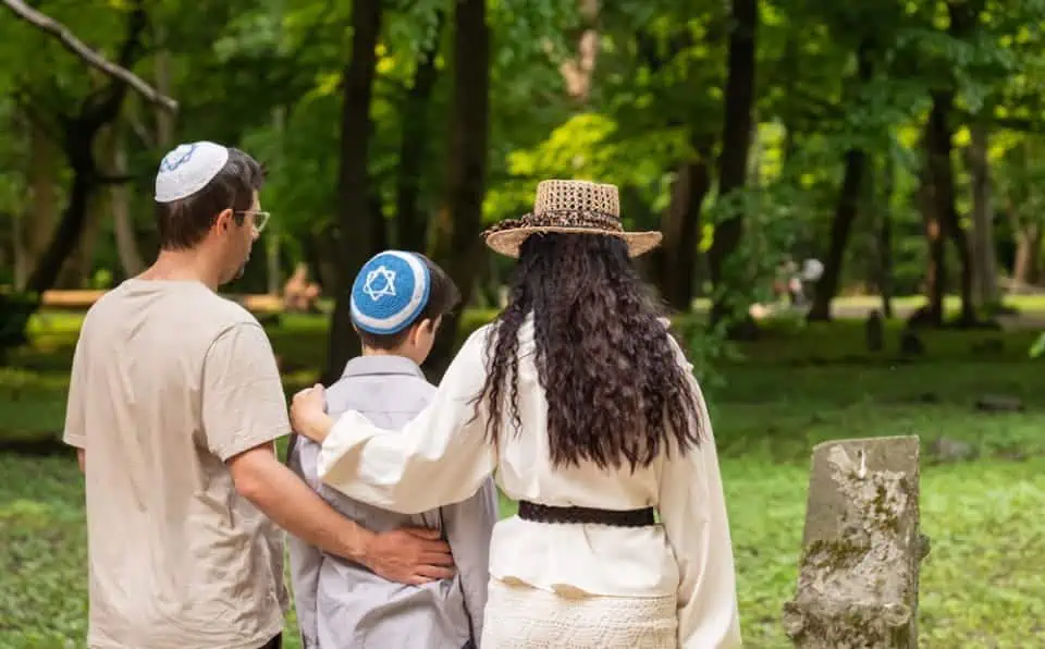 Family with two children visiting a cemetery in a park setting.