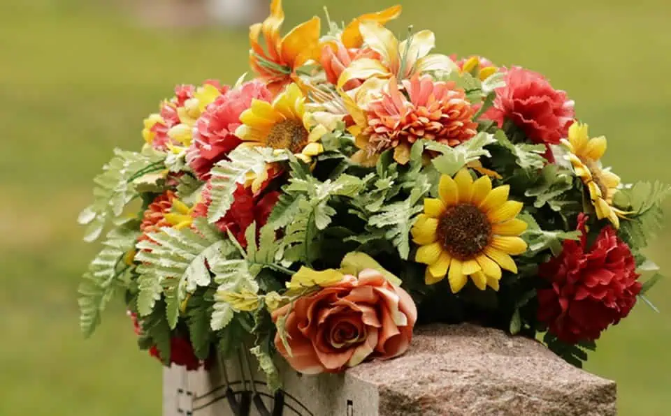 Vivid flower bouquet with sunflowers, roses, and other blooms on a stone.