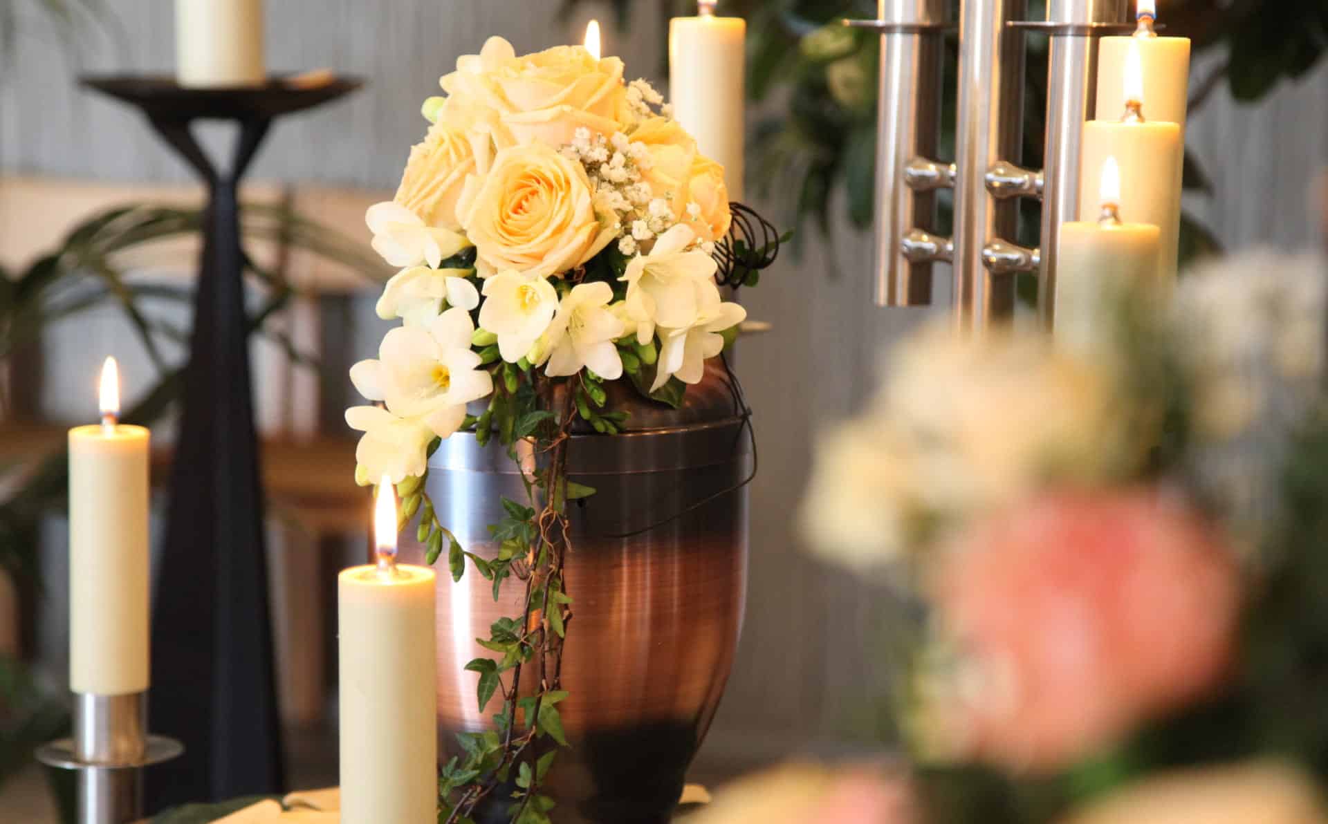 Beautiful floral arrangement with roses and orchids in a vase, surrounded by lit candles.