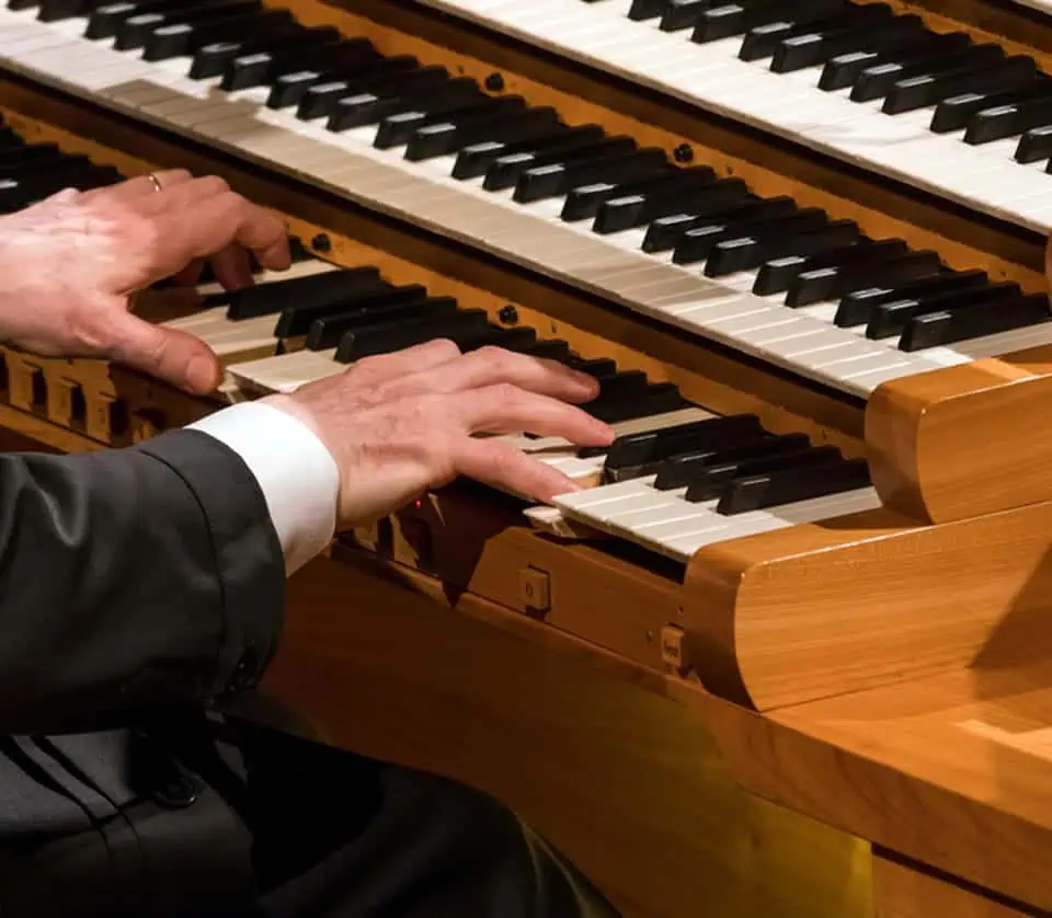 Close-up of hands playing a grand piano during a memorial event.