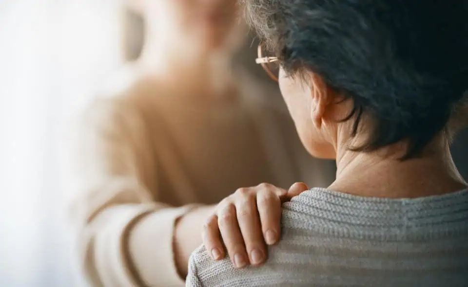 A caring person offers comfort to another individual in a warm, supportive gesture.