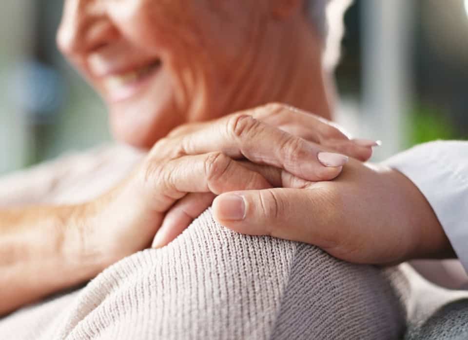 Close-up of two hands gently holding each other, showing compassion and support.