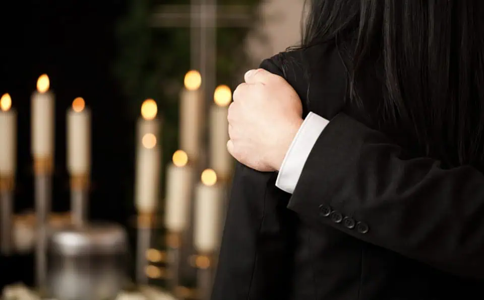 Person in black suit with hand on shoulder during private viewing.