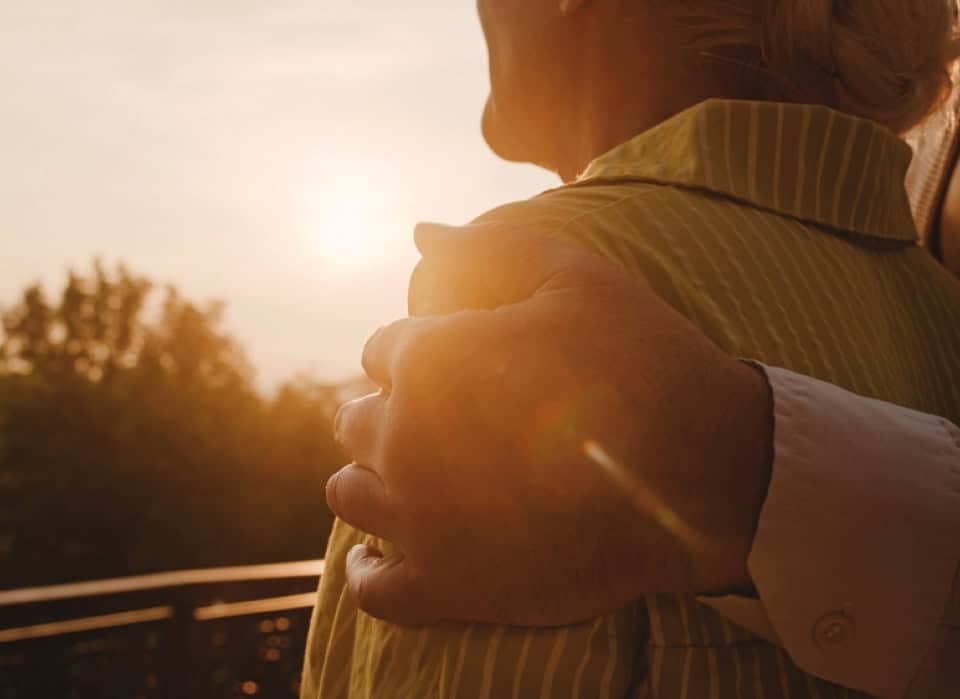 Close-up of two people embracing outdoors during sunset.