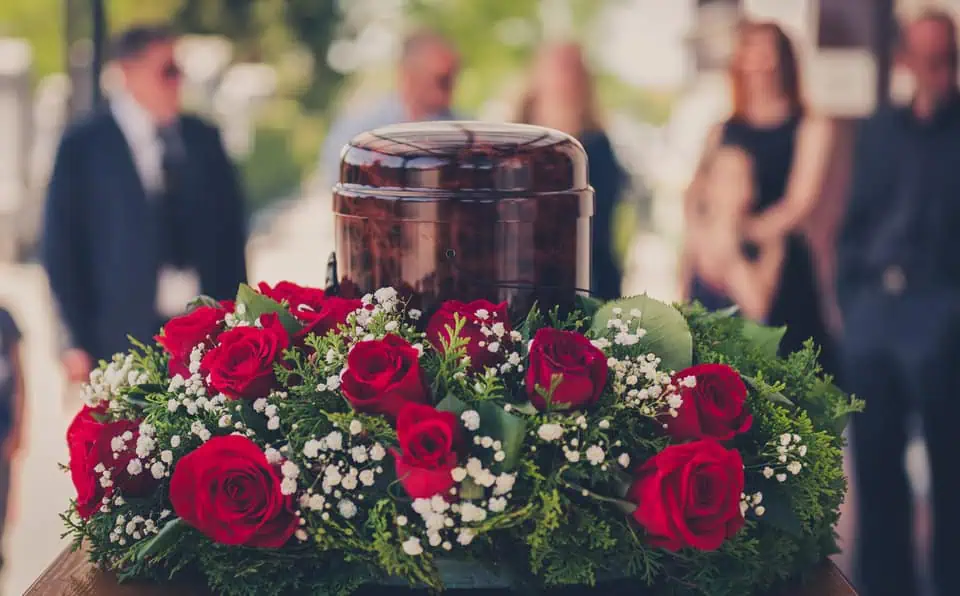 Wooden urn with a floral arrangement of red roses and white baby's breath.