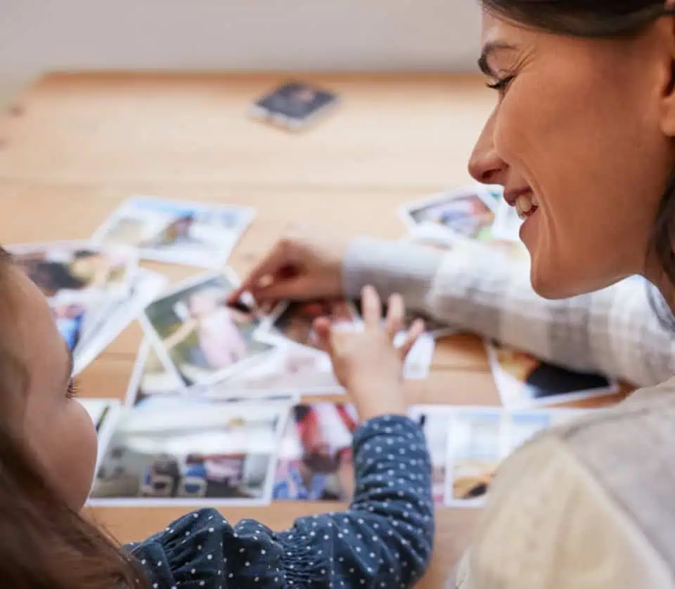 Woman and child looking at printed photographs at a table.
