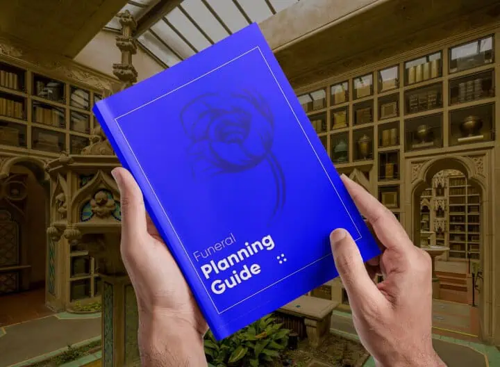Person holding a blue funeral planning guide in a library setting.