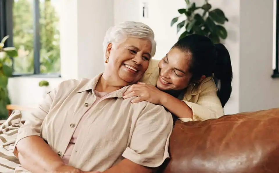 Grandmother and granddaughter sharing a joyful hug indoors.