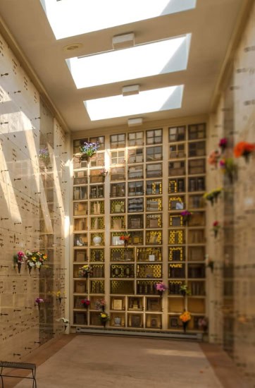 Interior view of a columbarium with multiple niches and skylights overhead.