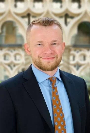 Portrait of a smiling man in a suit and tie outdoors.