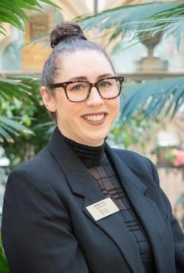 Smiling woman with glasses and bun hairstyle in professional attire at Chapel of the Chimes.