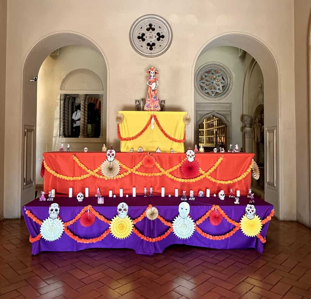 Chapel altar with colorful marigold garlands and skull decorations in a small memorial space.