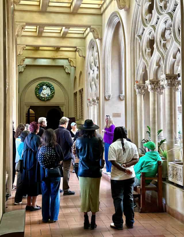 Chapel interior with group of visitors listening to guide near arched columns.