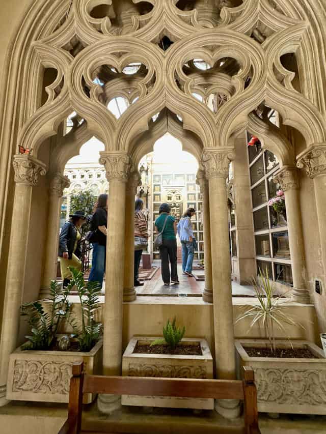 Chapel arches and courtyard seen through ornate arches in a historic indoor space.