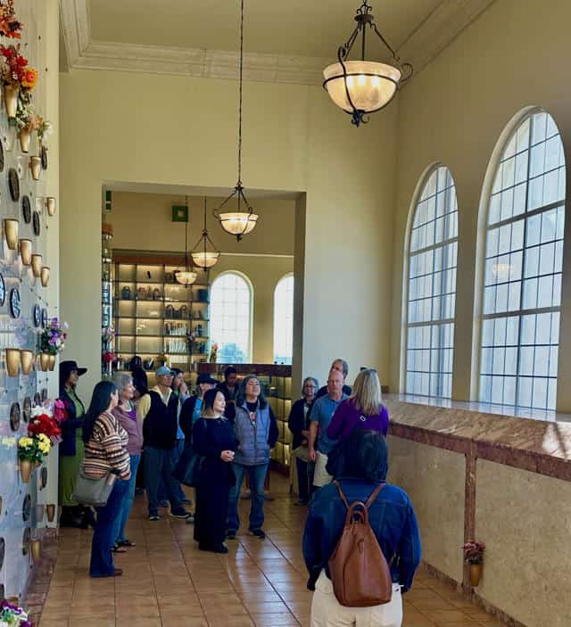 Chapel of the Chimes Oakland interior with visitors near memorial shelves and arched windows.